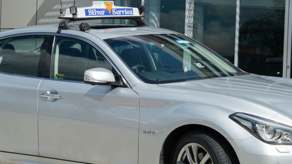 A silver taxi car, equipped with a prominent taxi sign on the front.